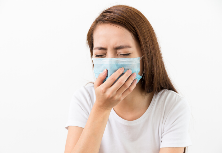 Woman wearing a mask coughing